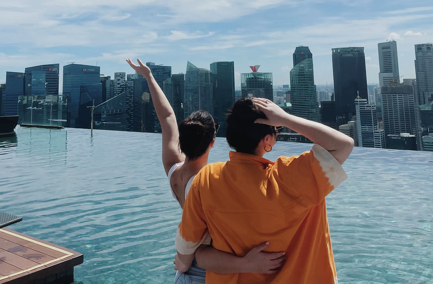 Two women standing in front of a rooftop city pool in Singapore.